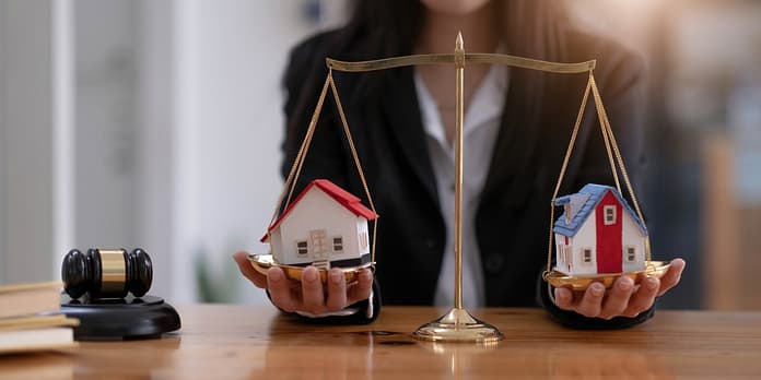 Female lawyer protecting a house model on a scales of justice. Property and legal concept. Houses