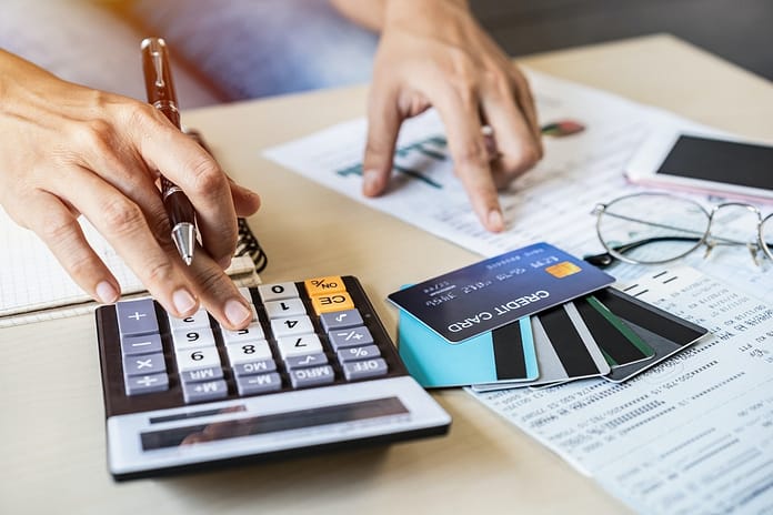 Young woman checking bills, taxes, bank account balance and calculating credit card expenses at home Young woman checking bills, taxes, bank account balance and calculating credit card expenses at home